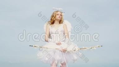 迷人的卷曲的小女孩穿着白色连衣裙和翅膀-天使丘比特女孩。 情人节礼品卡-圣诞少年丘比特